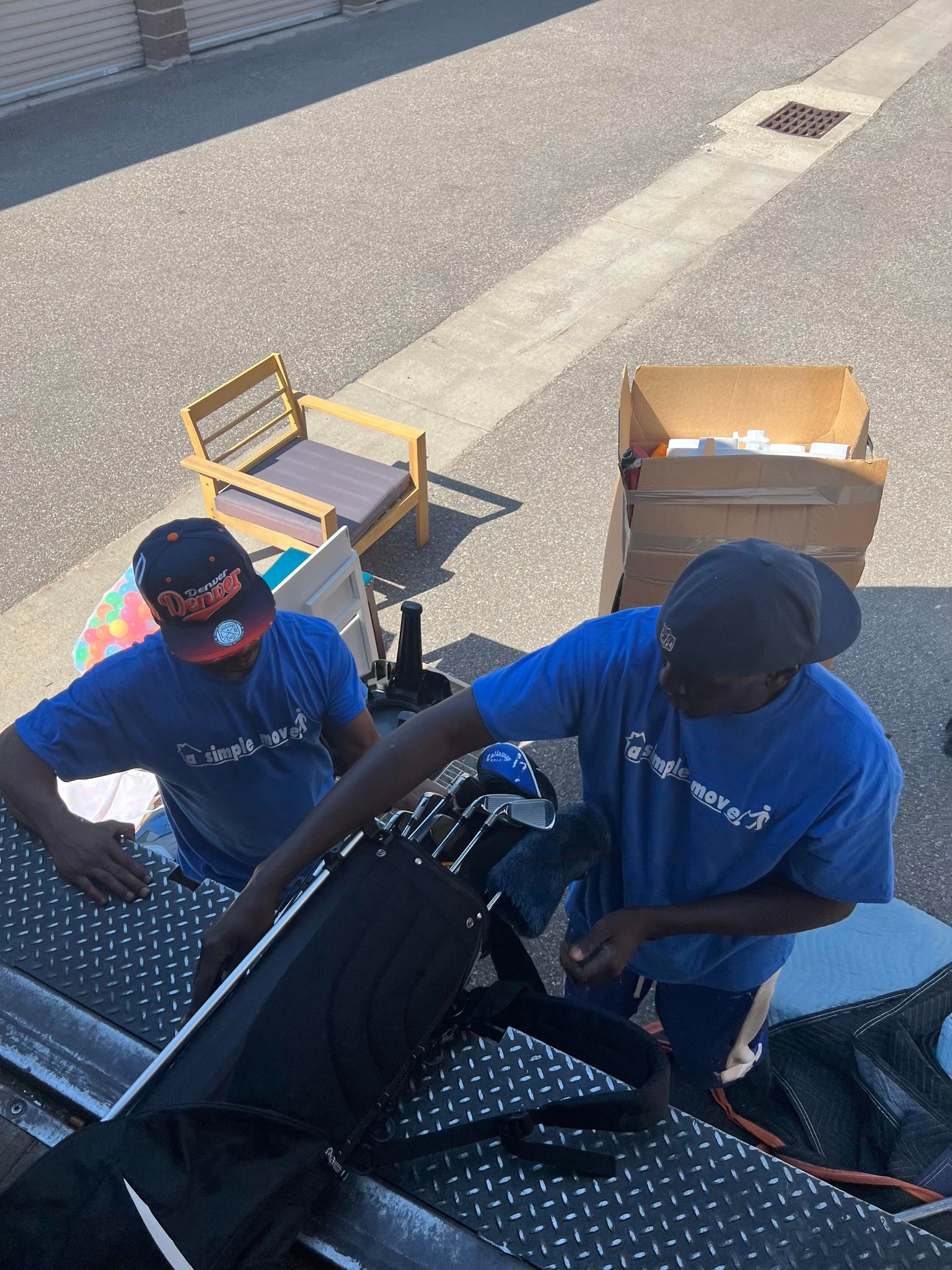 Two men in blue shirts are working on a laptop computer.