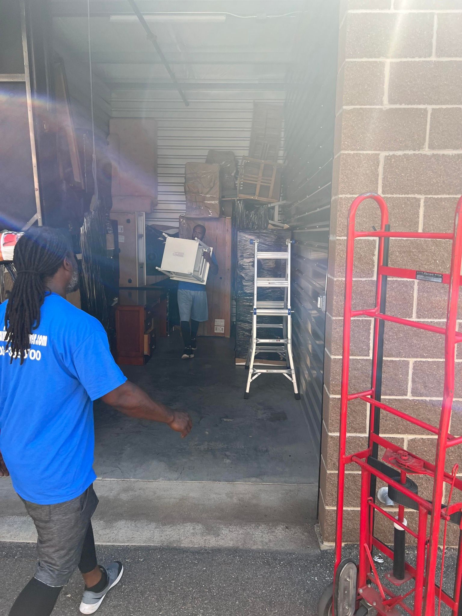 A man in a blue shirt is standing in front of a warehouse.