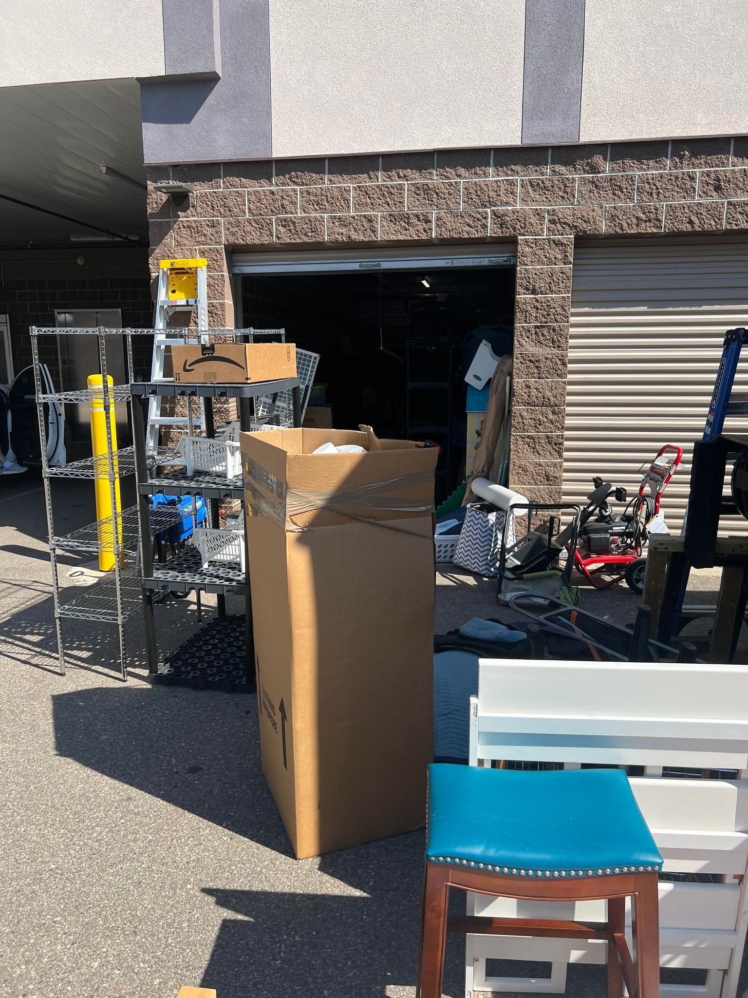 A cardboard box is sitting in front of a garage full of furniture.