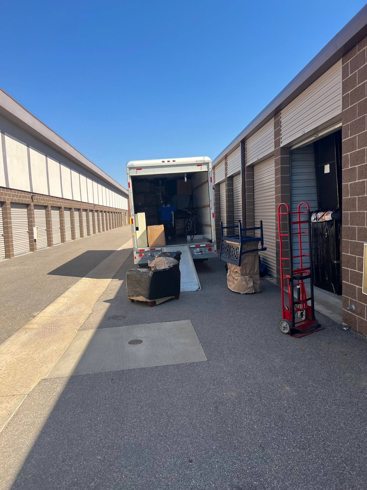 A moving truck is parked in a parking lot next to a building.