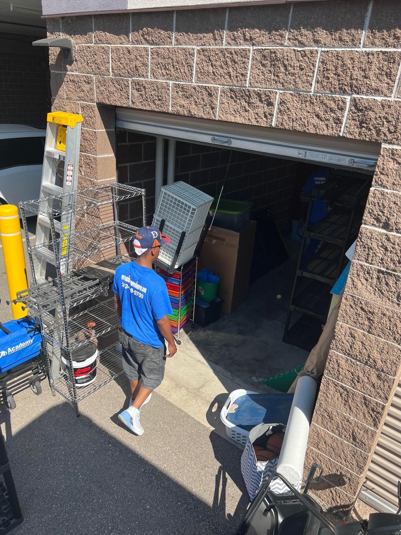 A man in a blue shirt is walking into a garage.