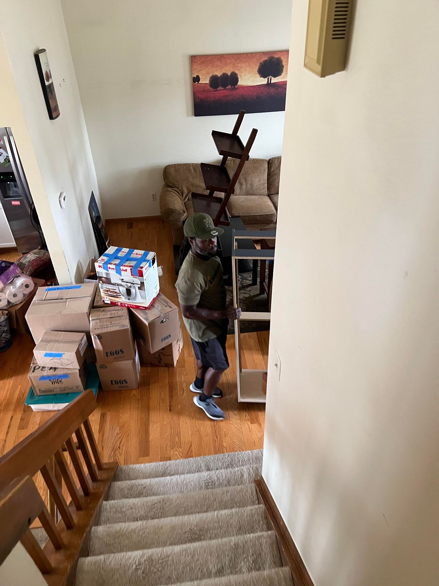 A man is standing in a living room surrounded by boxes.