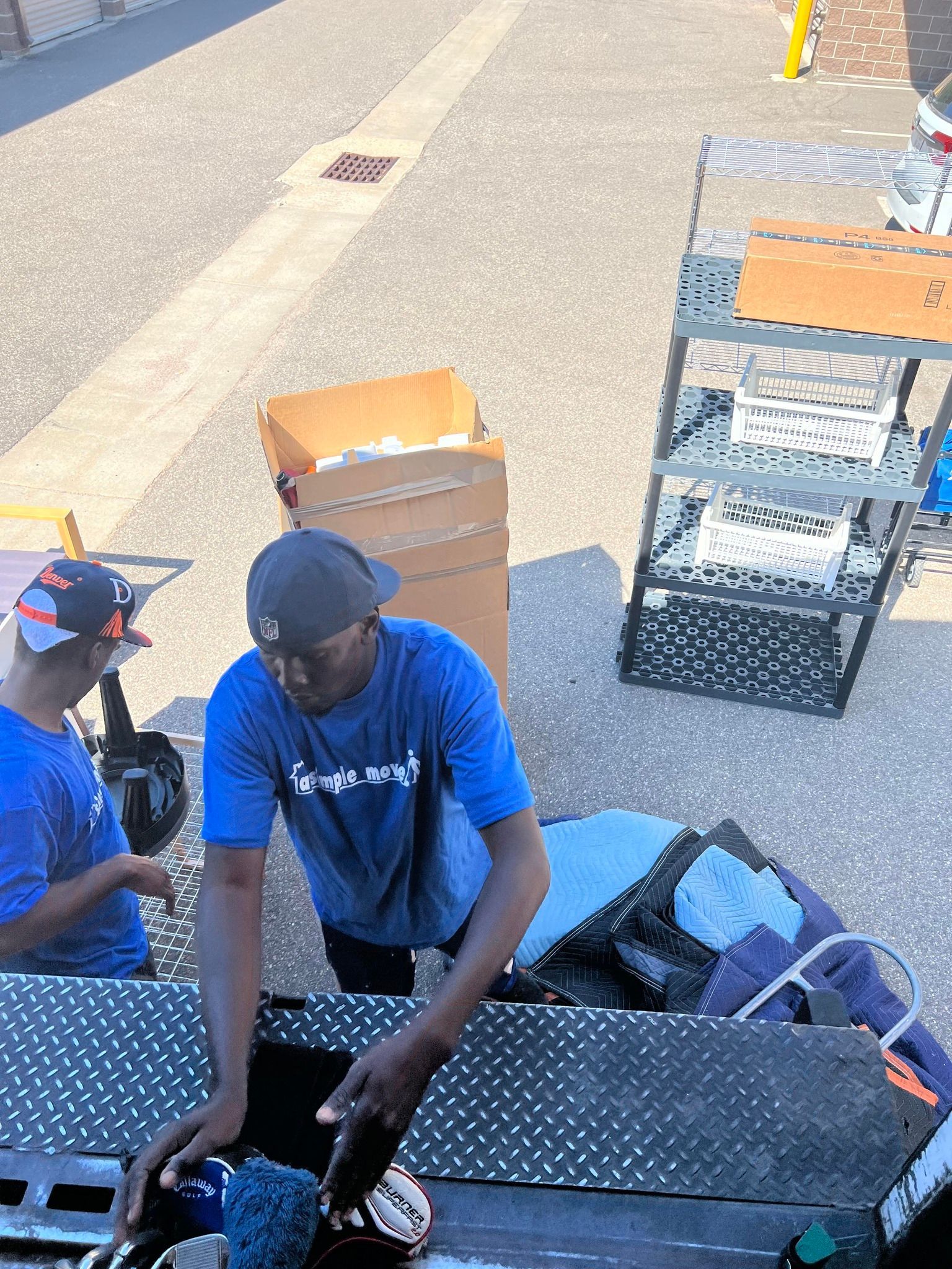 A man in a blue shirt is standing next to a man in a black hat.