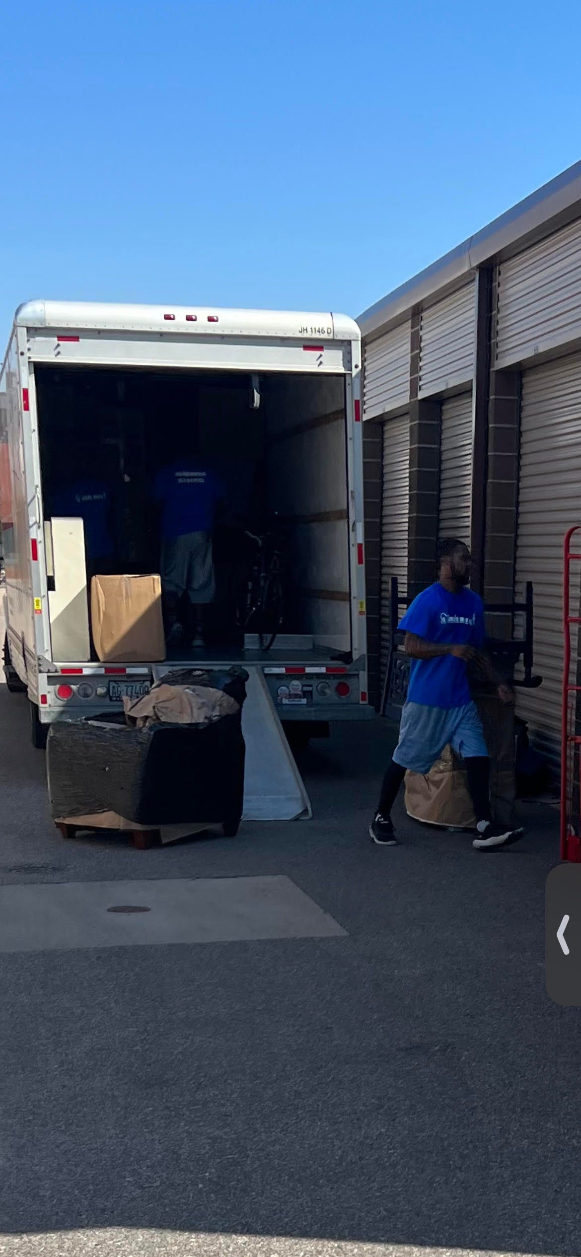 A man is pushing a dolly in front of a moving truck.