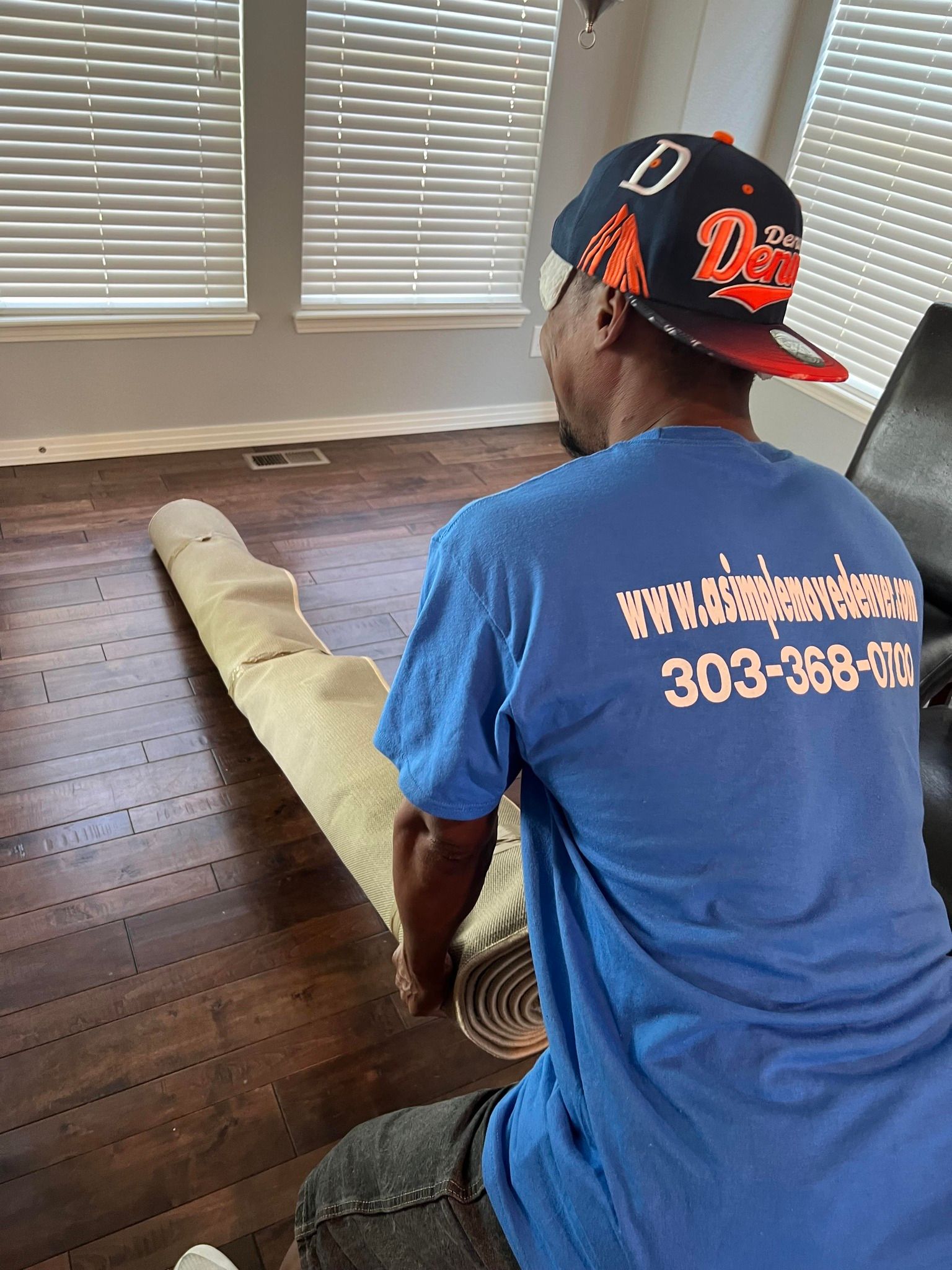 A man in a blue shirt is sitting on a couch holding a rug.