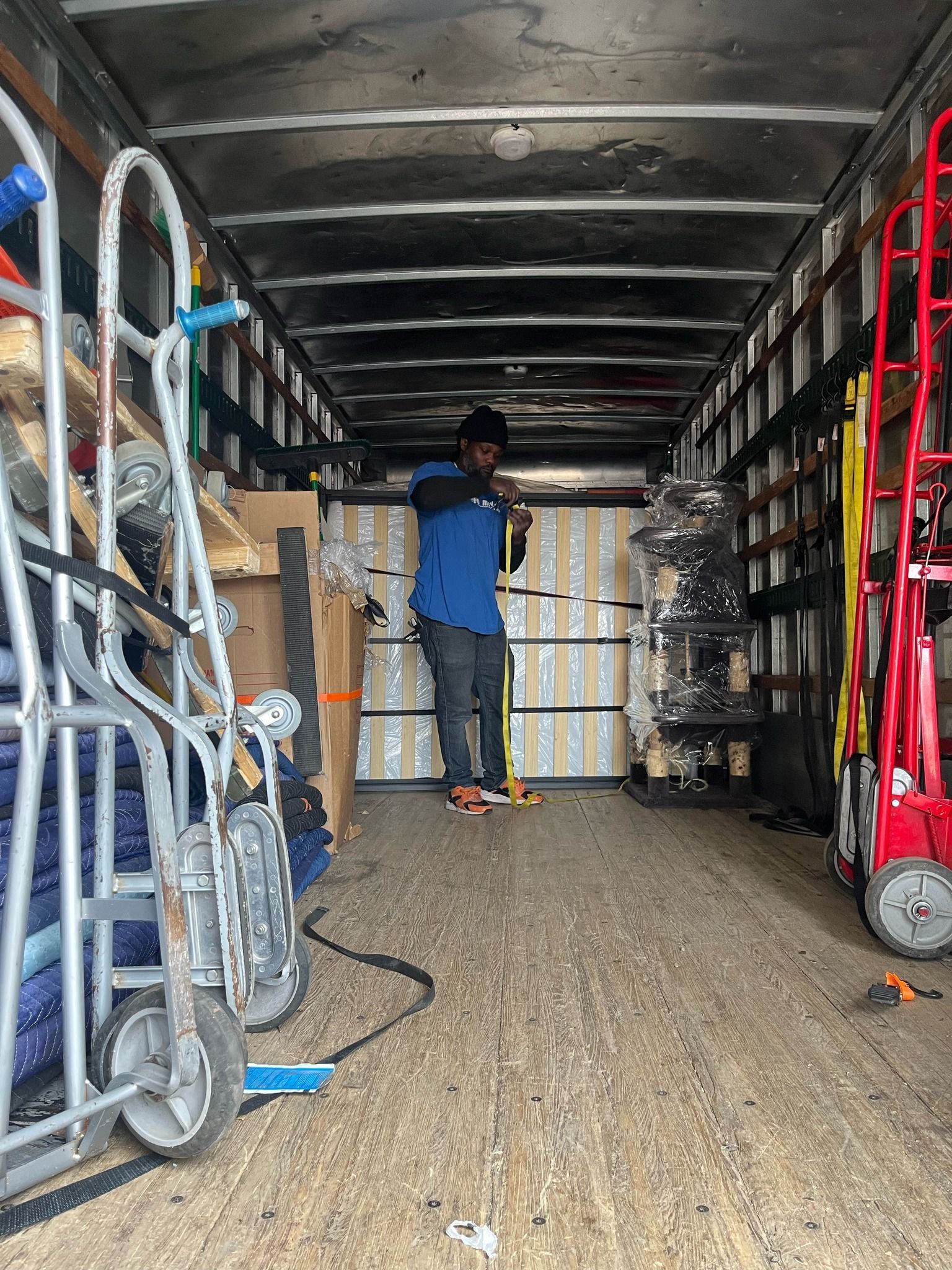 A man is standing in the back of a moving truck.