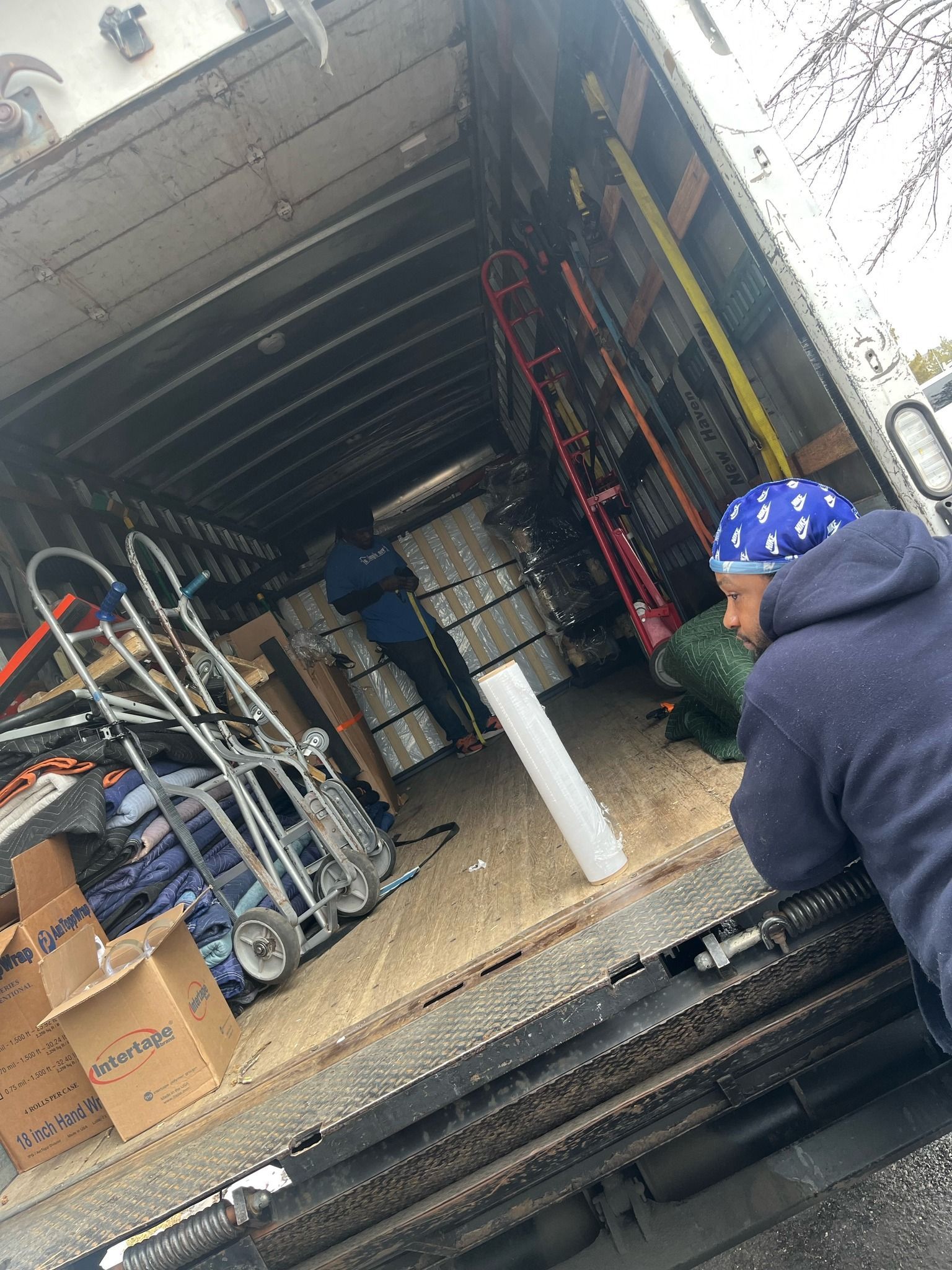 A man is sitting in the back of a moving truck.