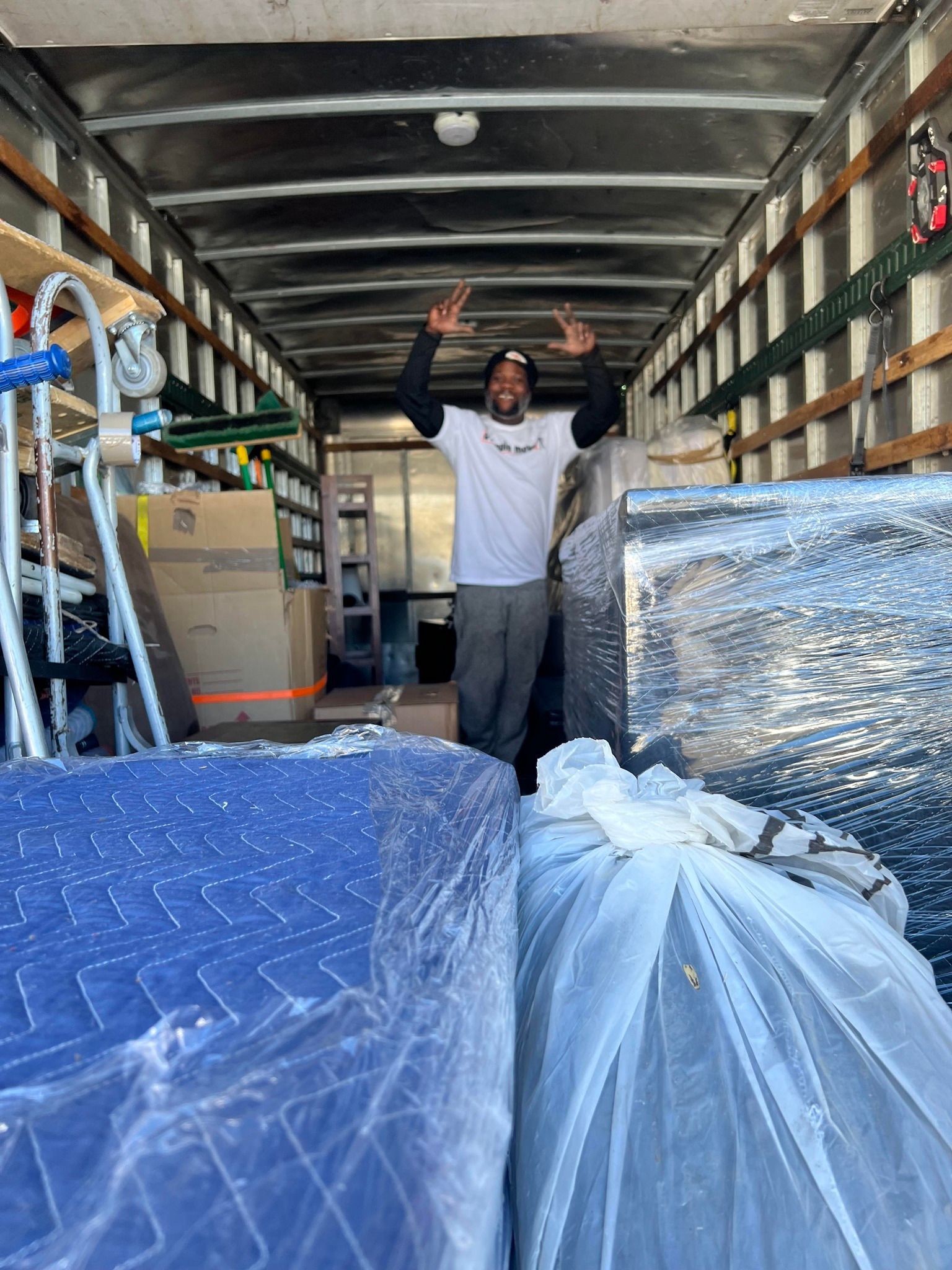 A man is standing in the back of a moving truck.