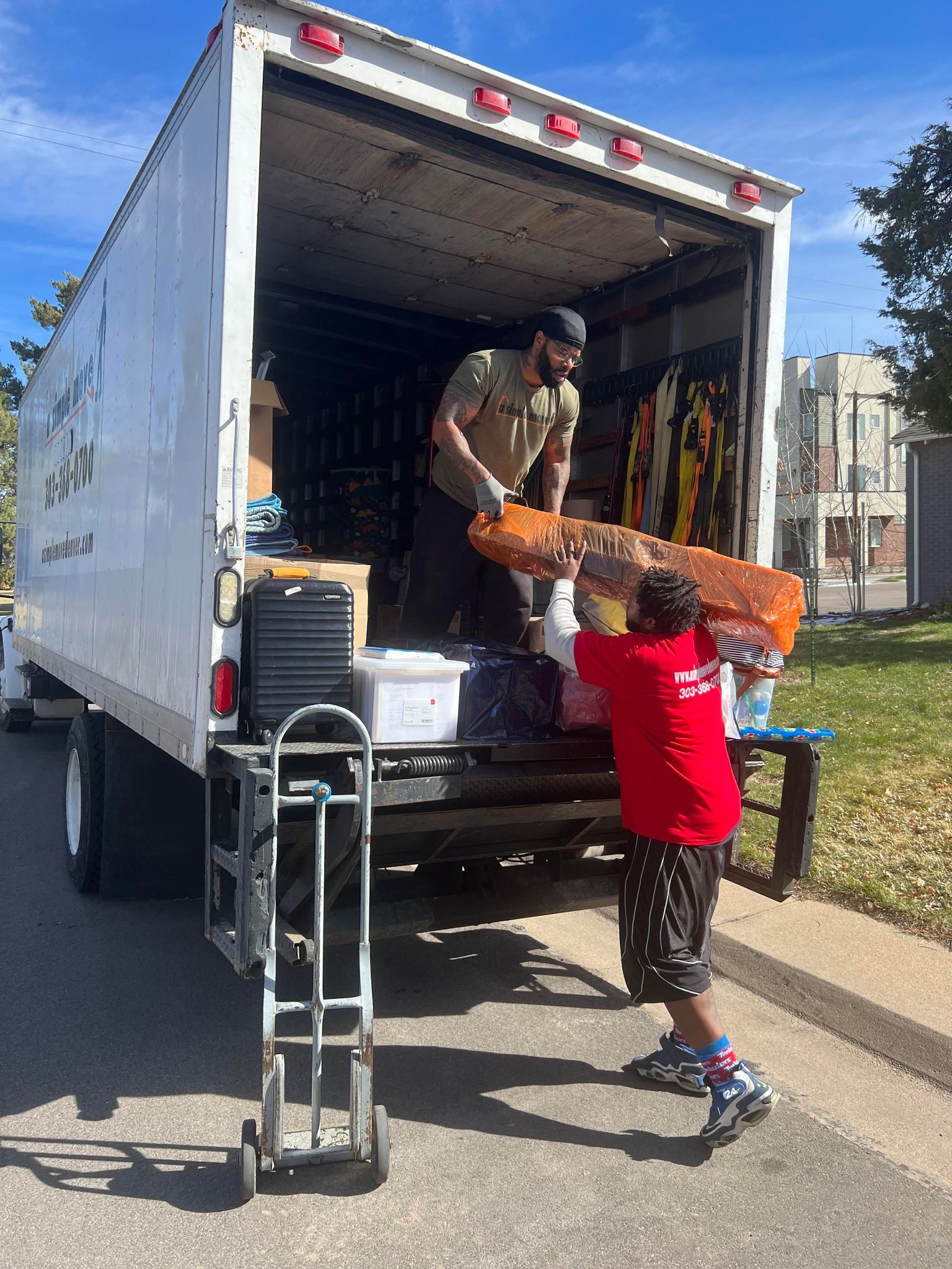 A man and a boy are loading a mattress into a moving truck.
