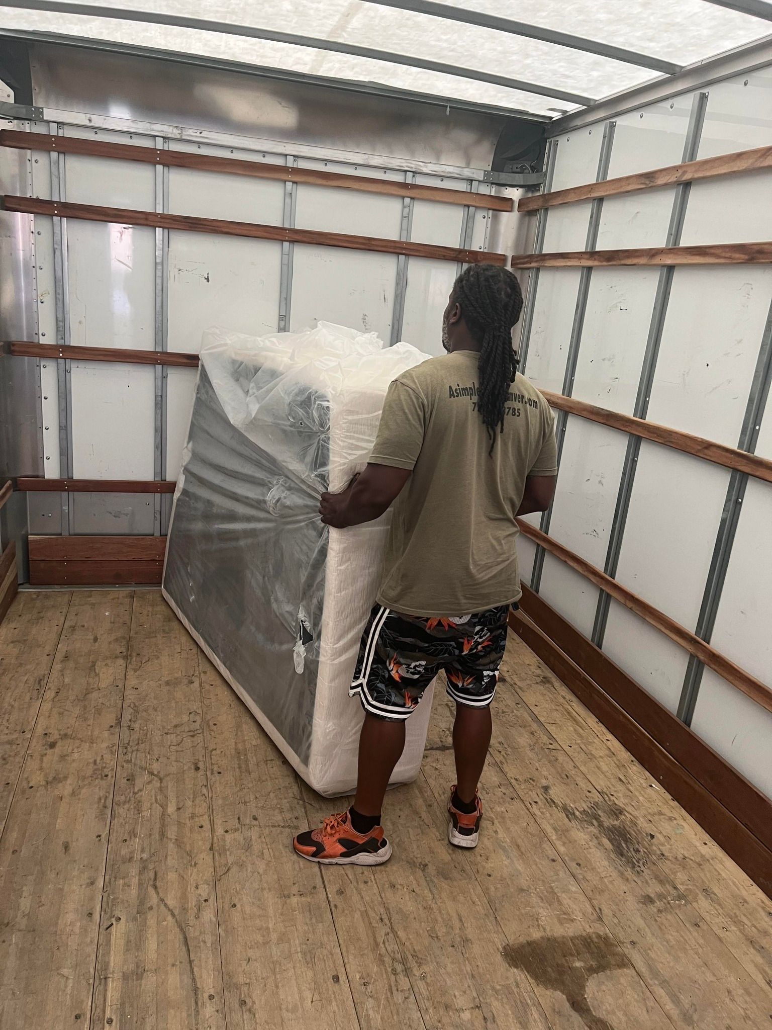 A man is carrying a mattress in a truck.