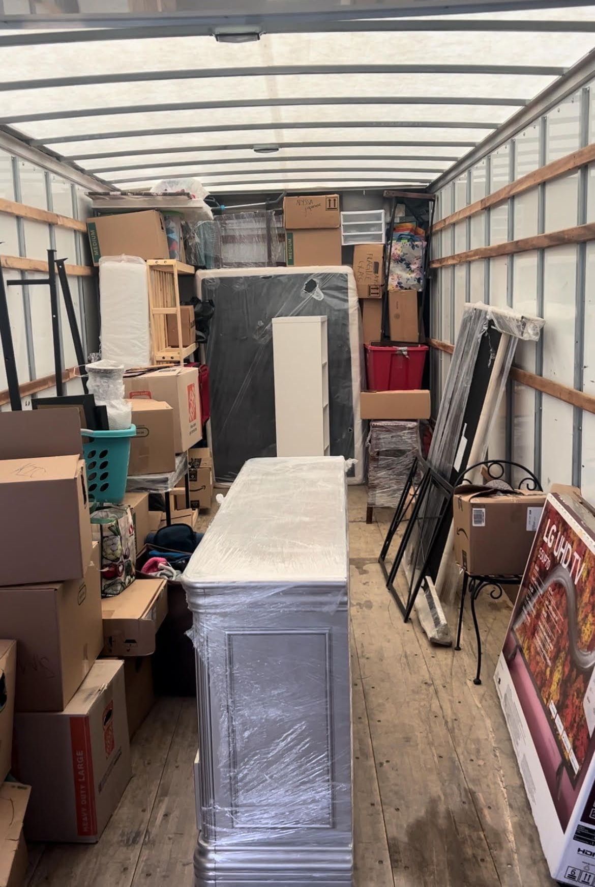 The inside of a moving truck filled with boxes and furniture.