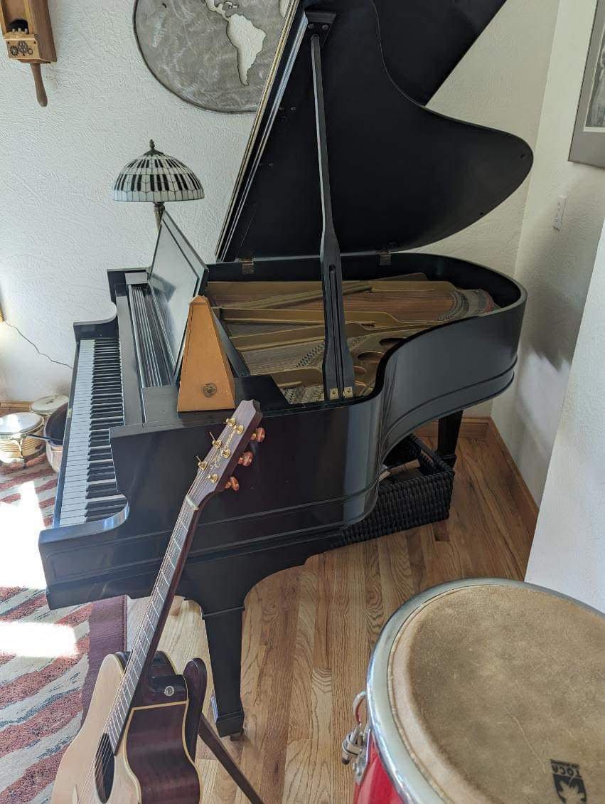 A piano is sitting in a room next to a drum and guitars.