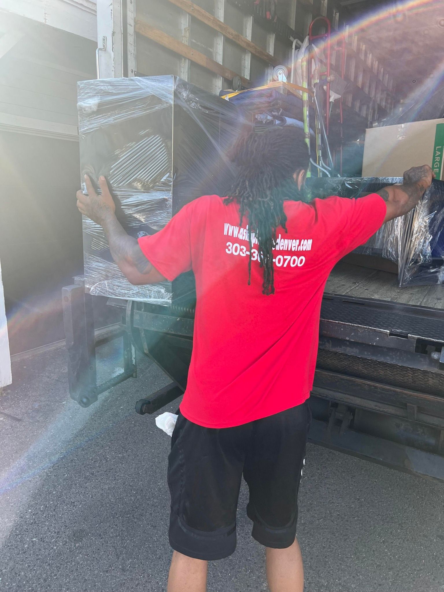 A man in a red shirt is standing in front of a truck holding a piece of glass.