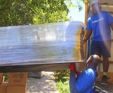 A man in a blue shirt is carrying a large piece of plastic wrap.