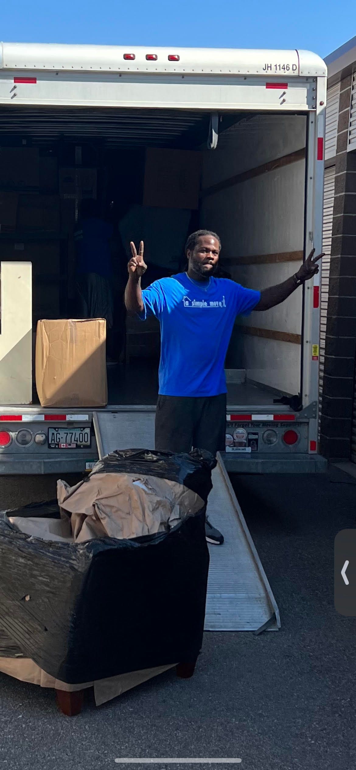 A man in a blue shirt is standing in front of a moving truck.