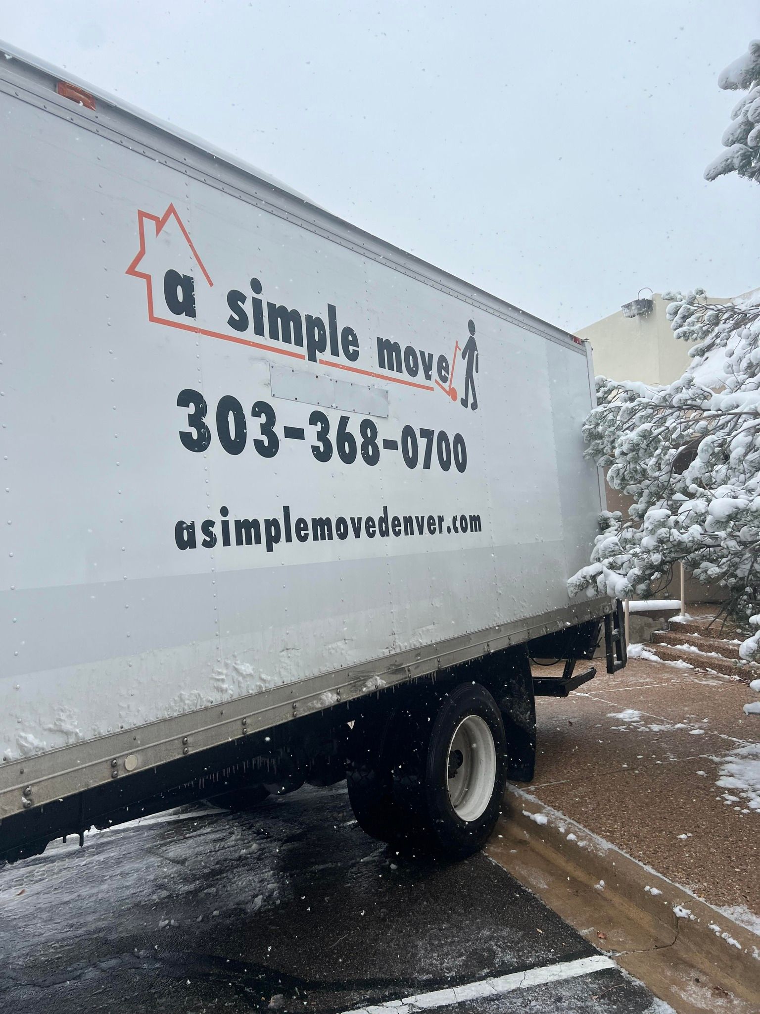 A white moving truck is parked in a snowy parking lot.