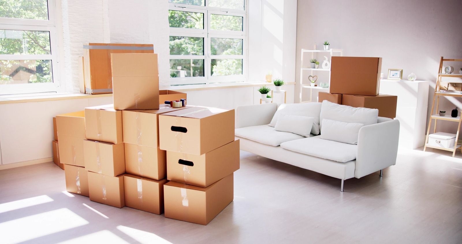 A living room filled with cardboard boxes and a white couch.