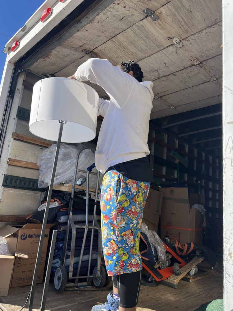 A man is standing in the back of a truck holding a lamp.