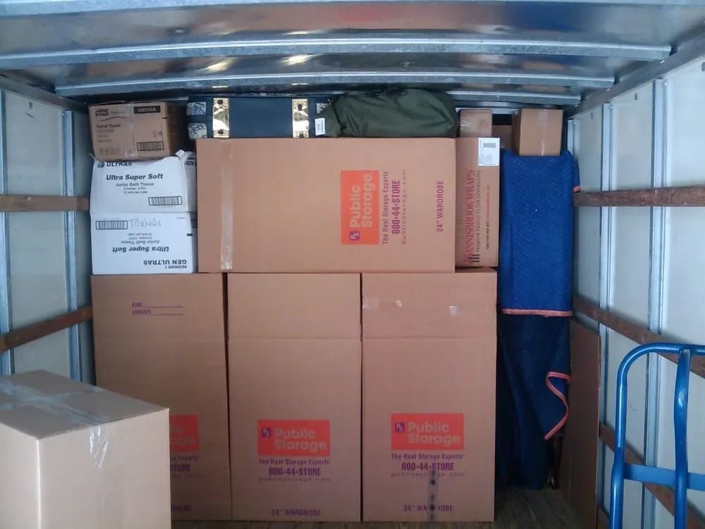 The inside of a moving truck filled with boxes and a mattress