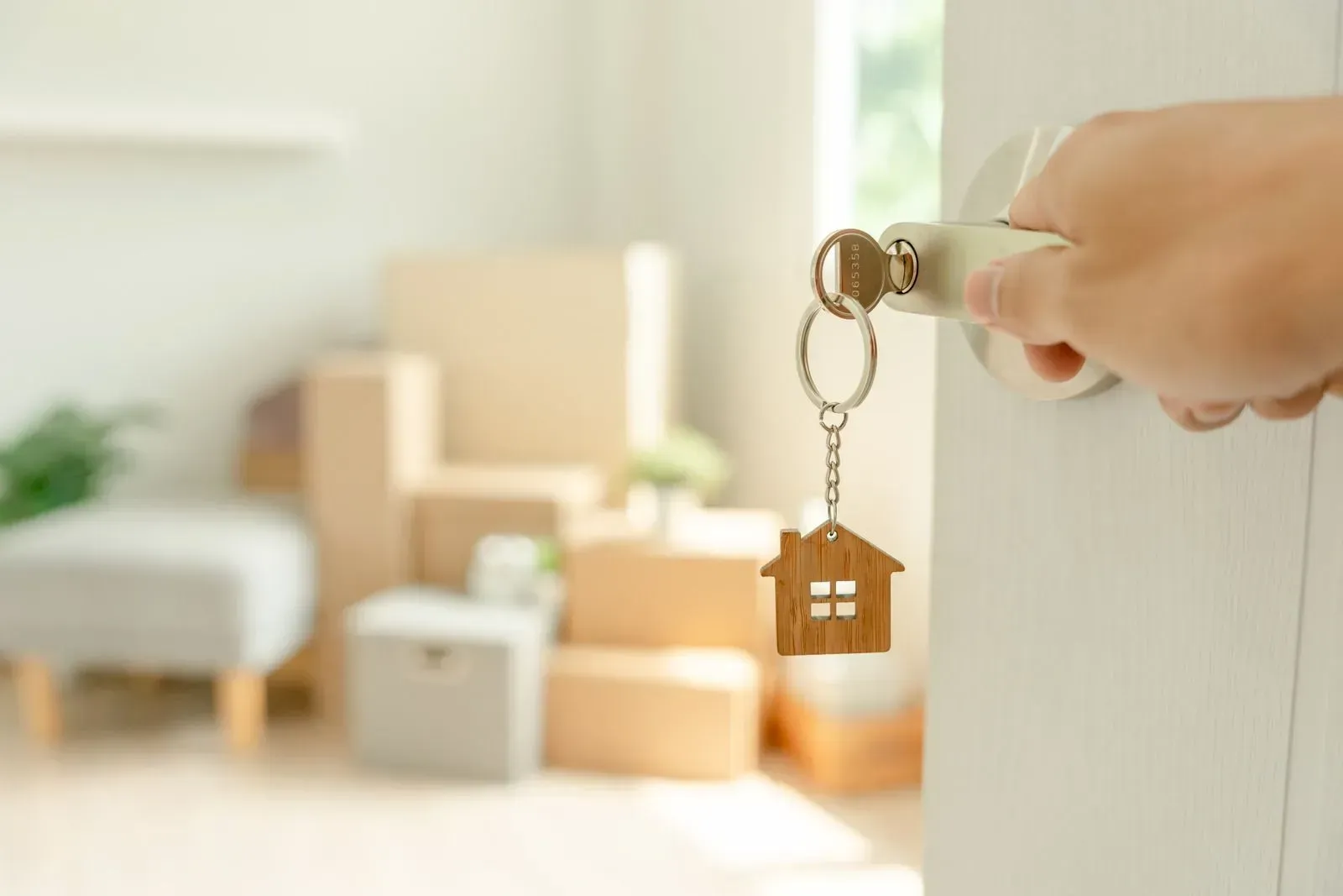 A person is opening a door with a key and a house keychain.