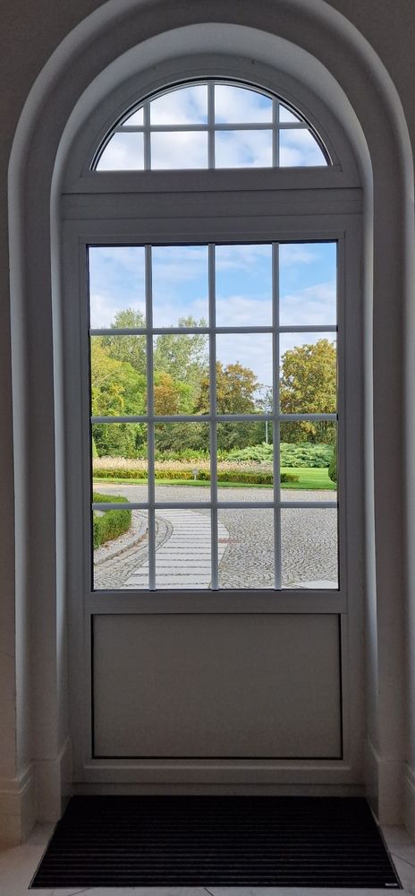 Una porta bianca con vista su un parco attraverso una finestra.