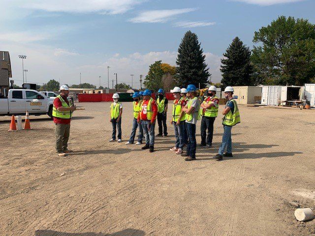 A group of construction workers are standing in a dirt field