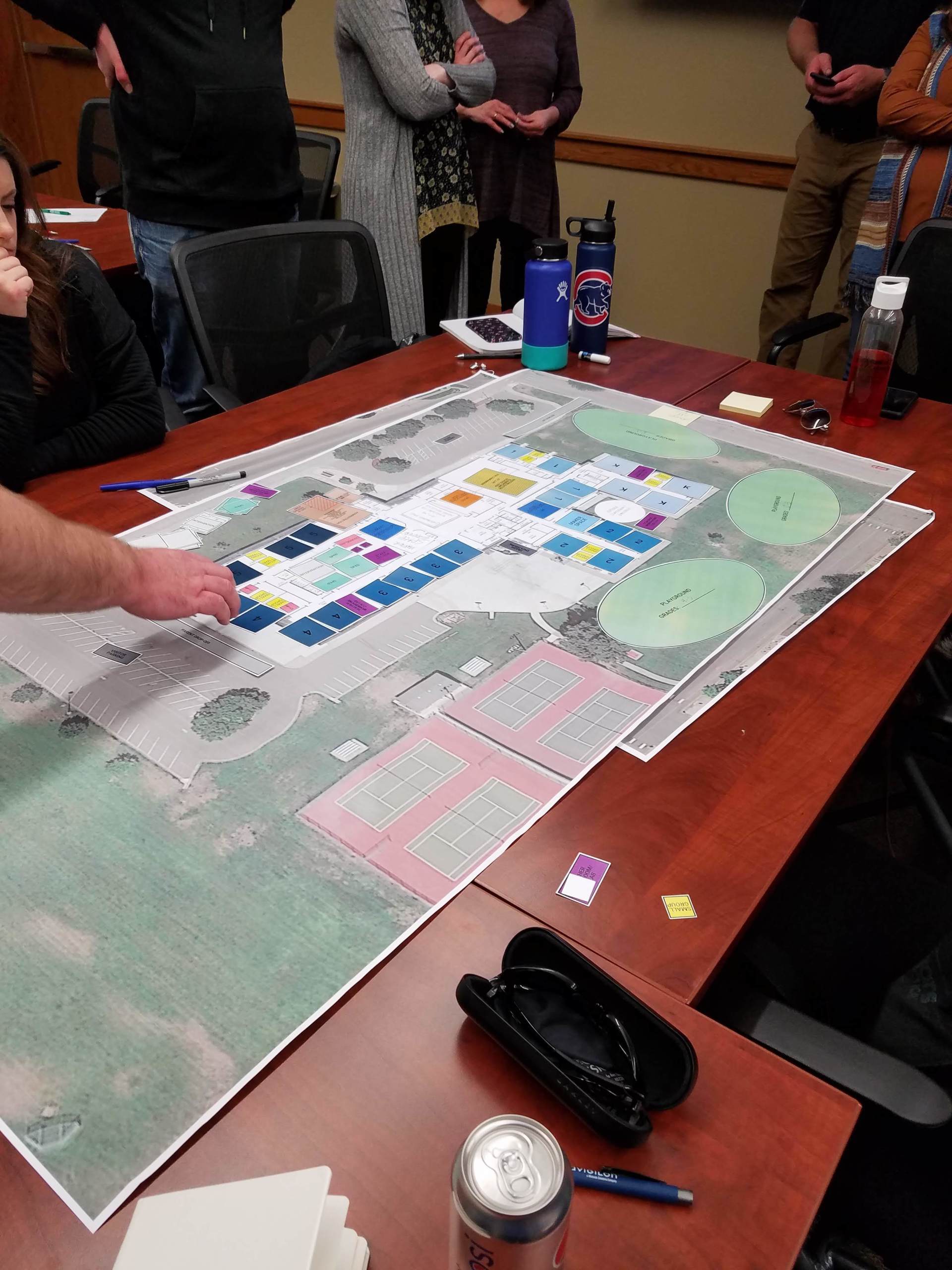 A group of people are sitting around a table with a large map on it