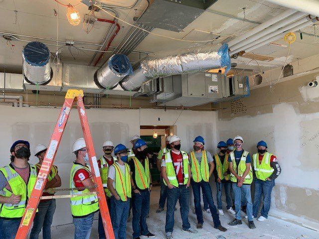 A group of construction workers are standing in a room with a ladder.