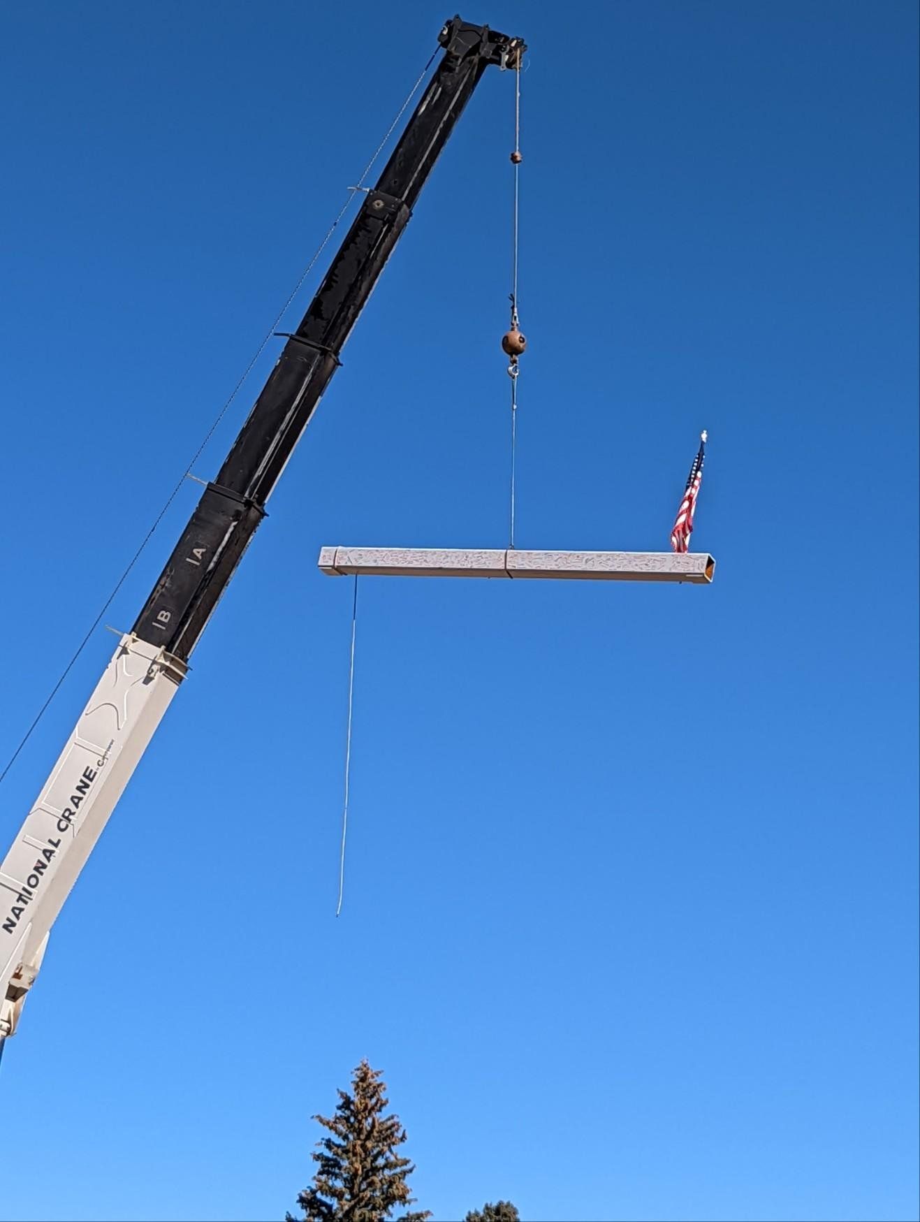 A crane is lifting a large piece of wood in the air