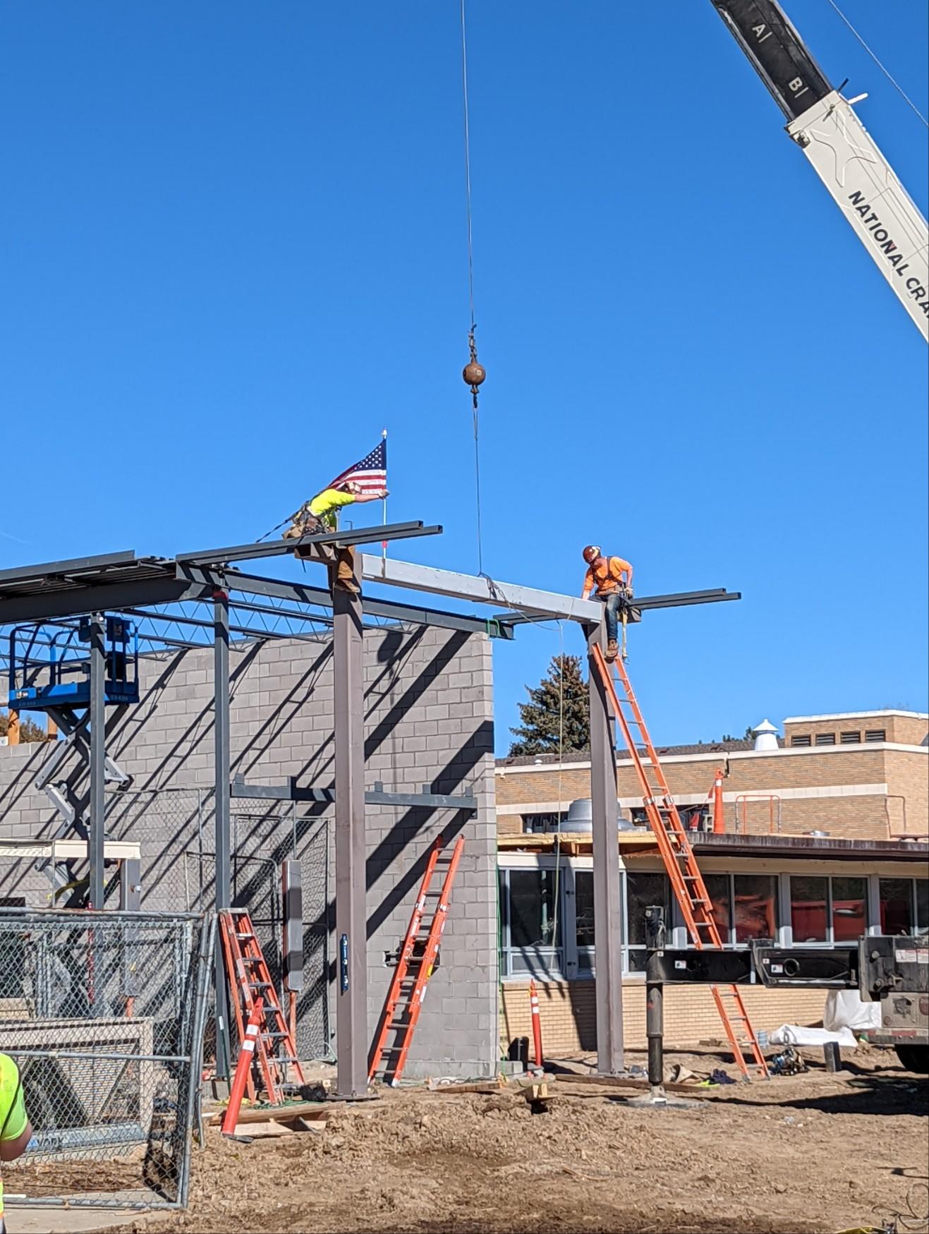 A crane is lifting a beam on a construction site.
