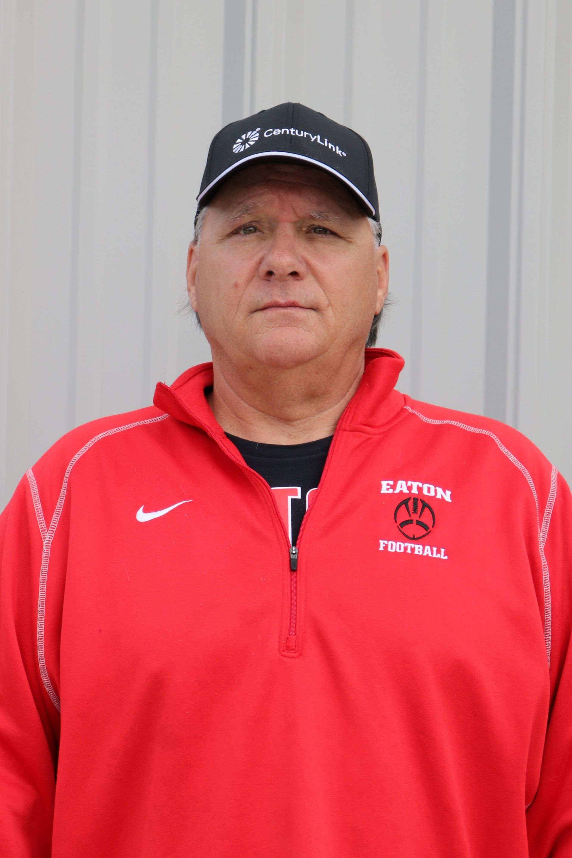 A man wearing a red nike jacket and a black hat