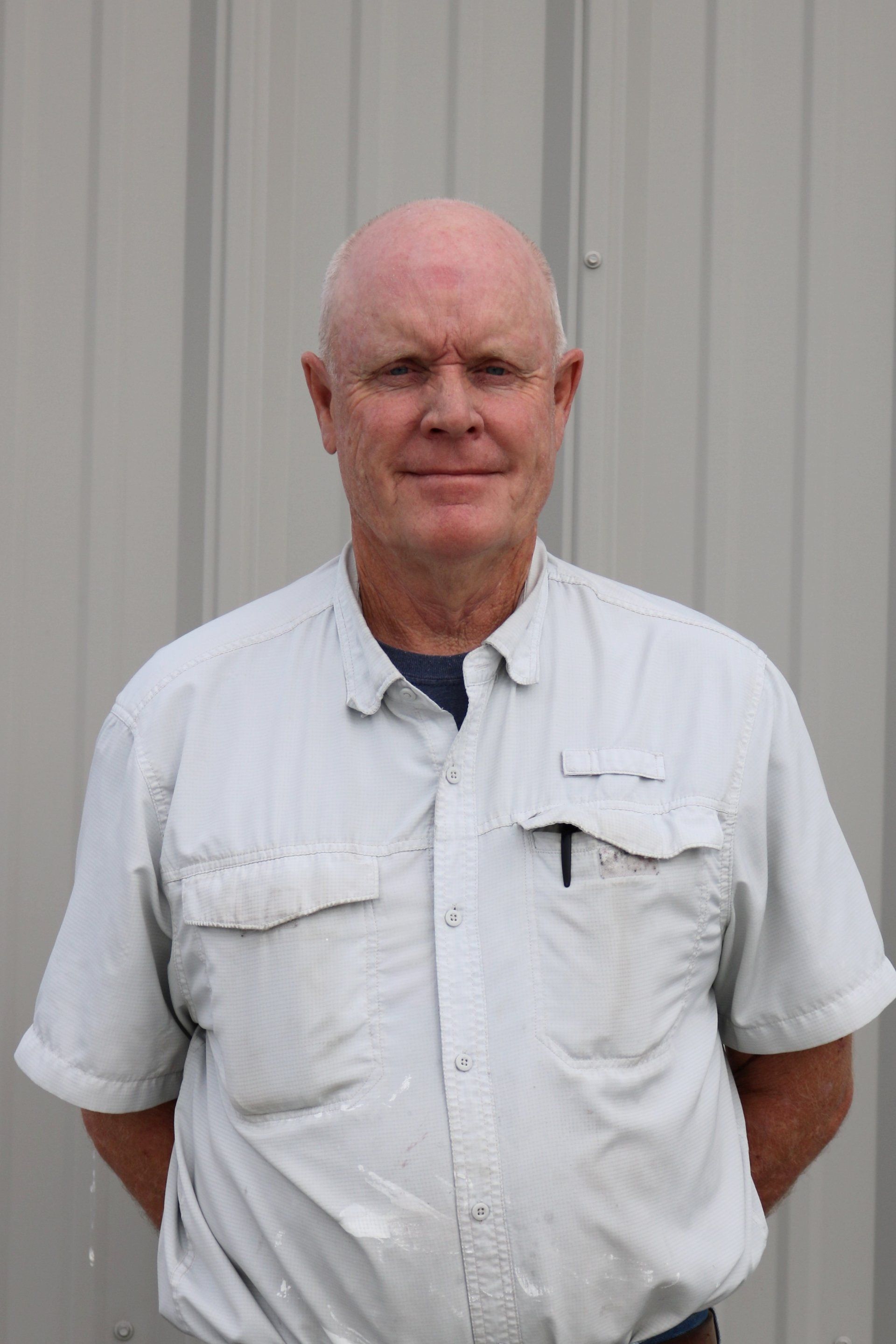 A man in a white shirt is standing in front of a building.