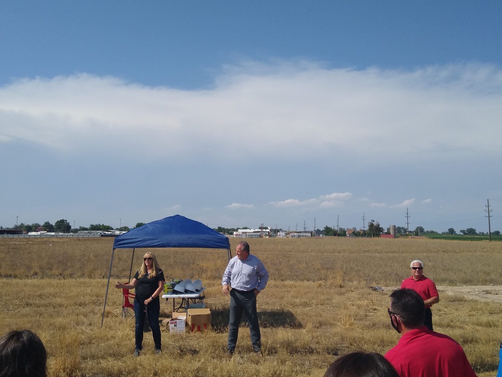 A group of people standing in a field with a blue tent in the background