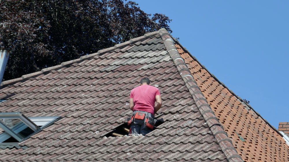 A Man Working Repair Of A Tile Roof — Munro Building Group In Cleveland, QLD