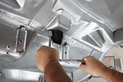 a man is working on the hood of a car with a wrench