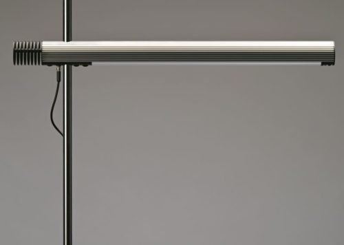 Eine Nahaufnahme einer Lampe auf einem Ständer vor grauem Hintergrund.