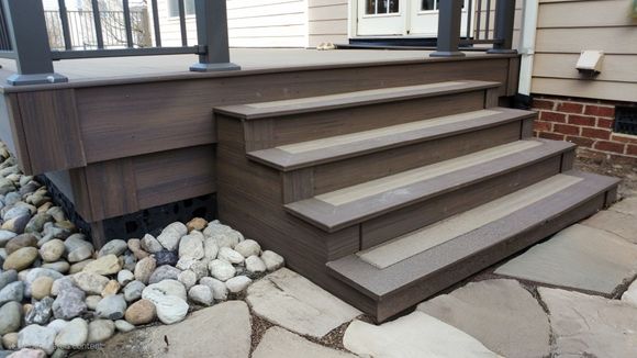 Wooden deck steps leading to a porch with stone landscaping.
