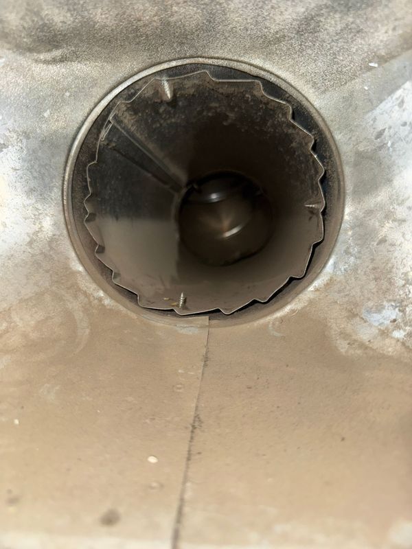 A close-up view of a dusty, metallic tube with visible debris inside the opening.