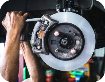 A man is working on a brake disc on a car. | NRH Automotive