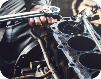 A man is working on a car engine with a wrench. | NRH Automotive