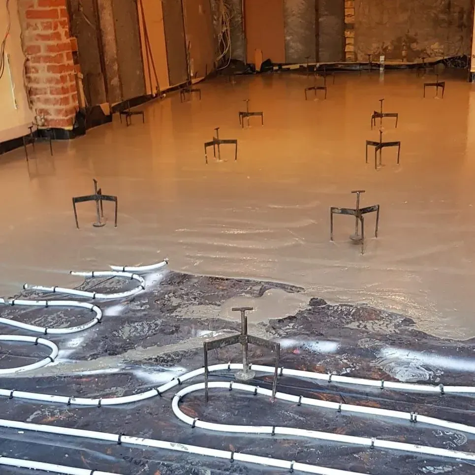 Pumping liquid screed flooring over a newly-installed undefloor heating system.