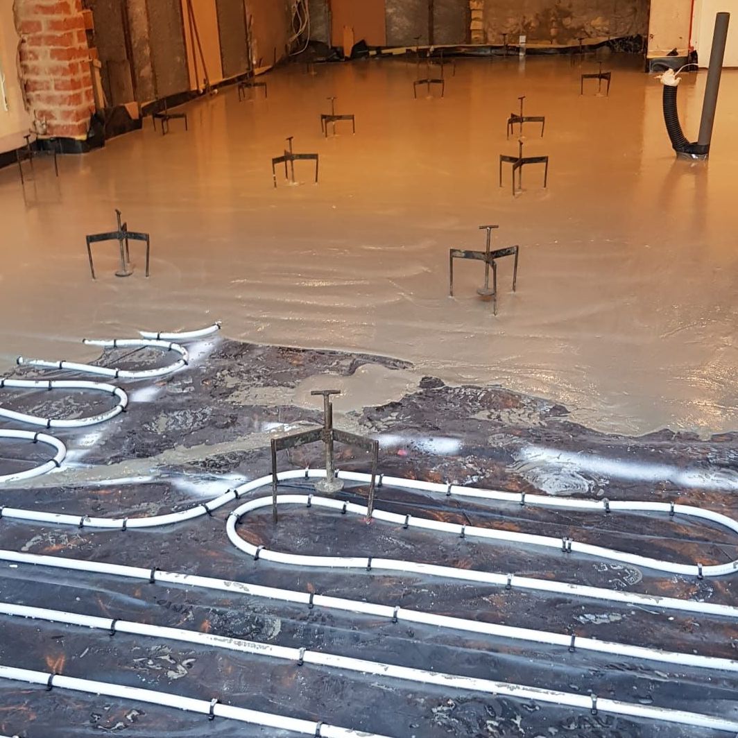 Room with underfloor heating system installed, part way through the liquid screed installation process.