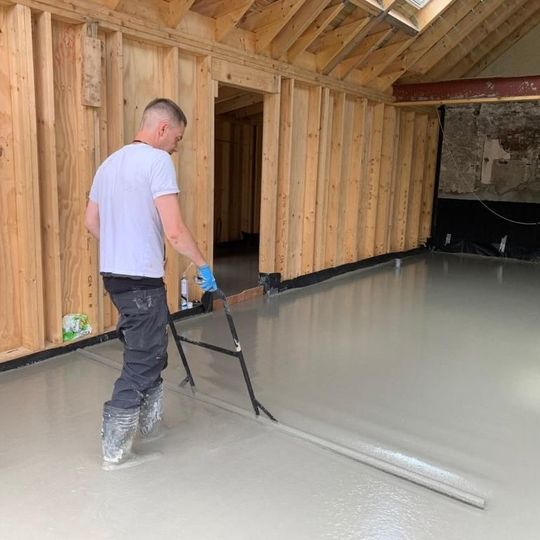 One of our installers hand levelling a freshly pumped screed floor.