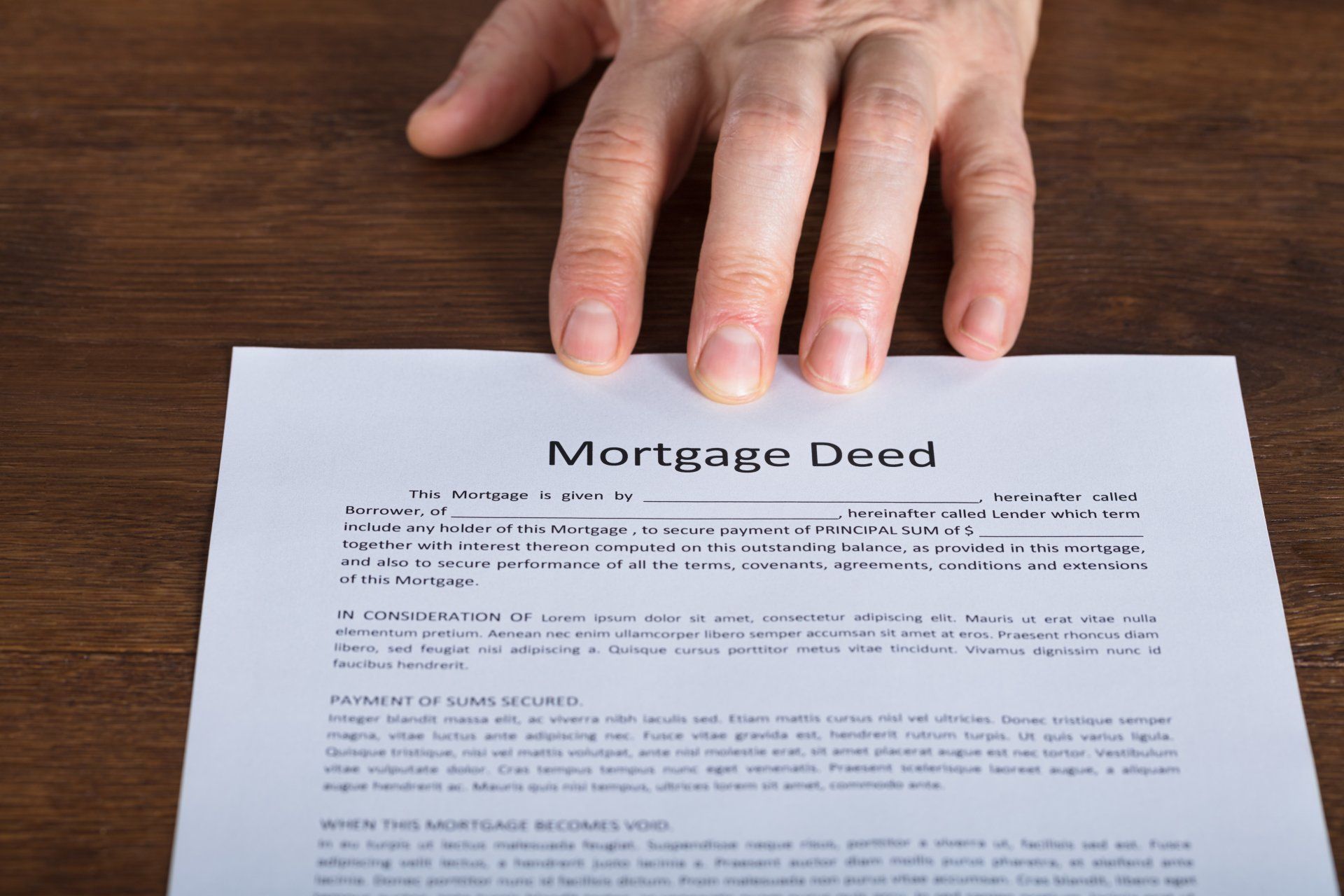 A person is holding a piece of paper that says mortgage deed.