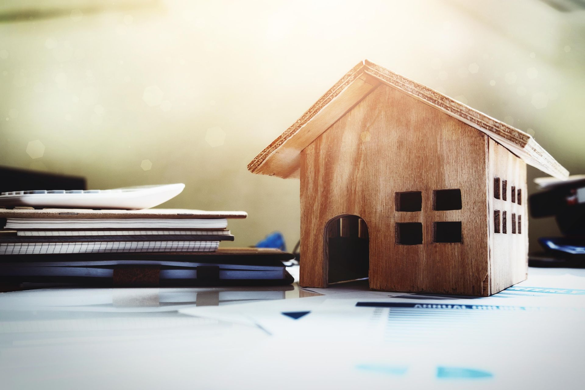 A small wooden house is sitting on top of a stack of books.