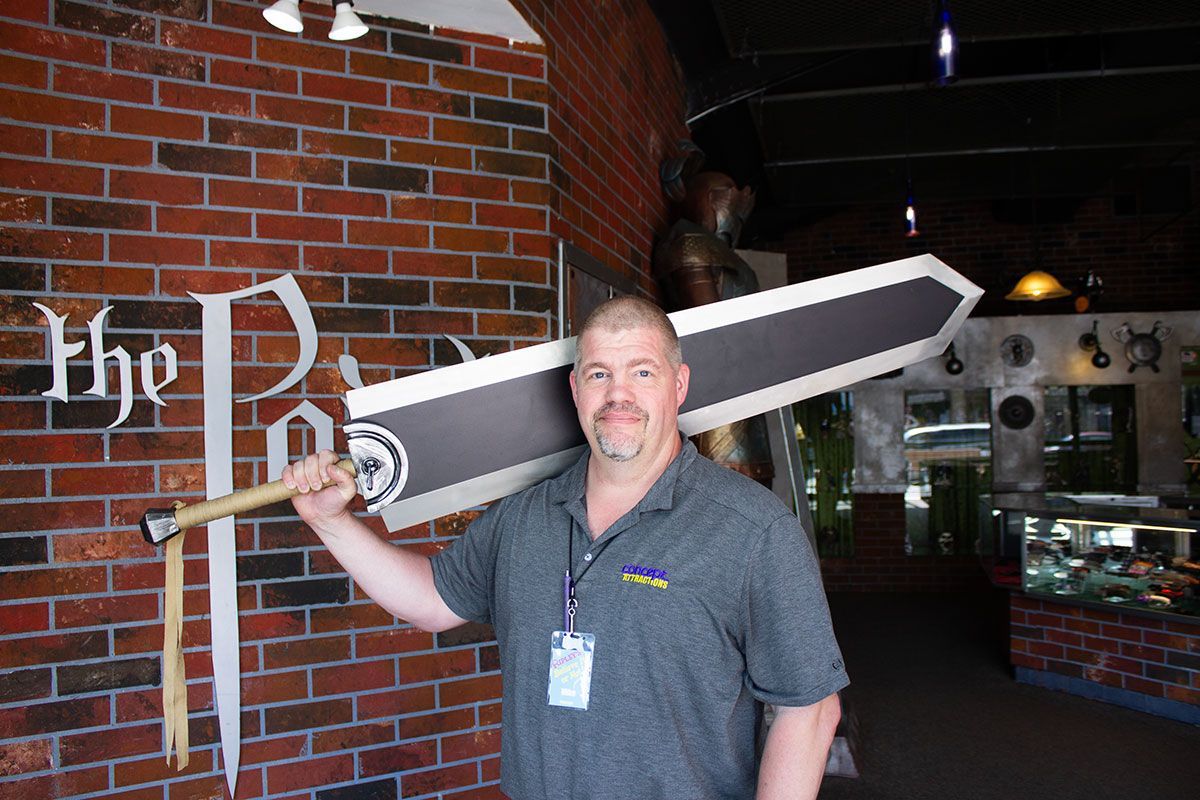 Man holding large sword in front of sign for The Point