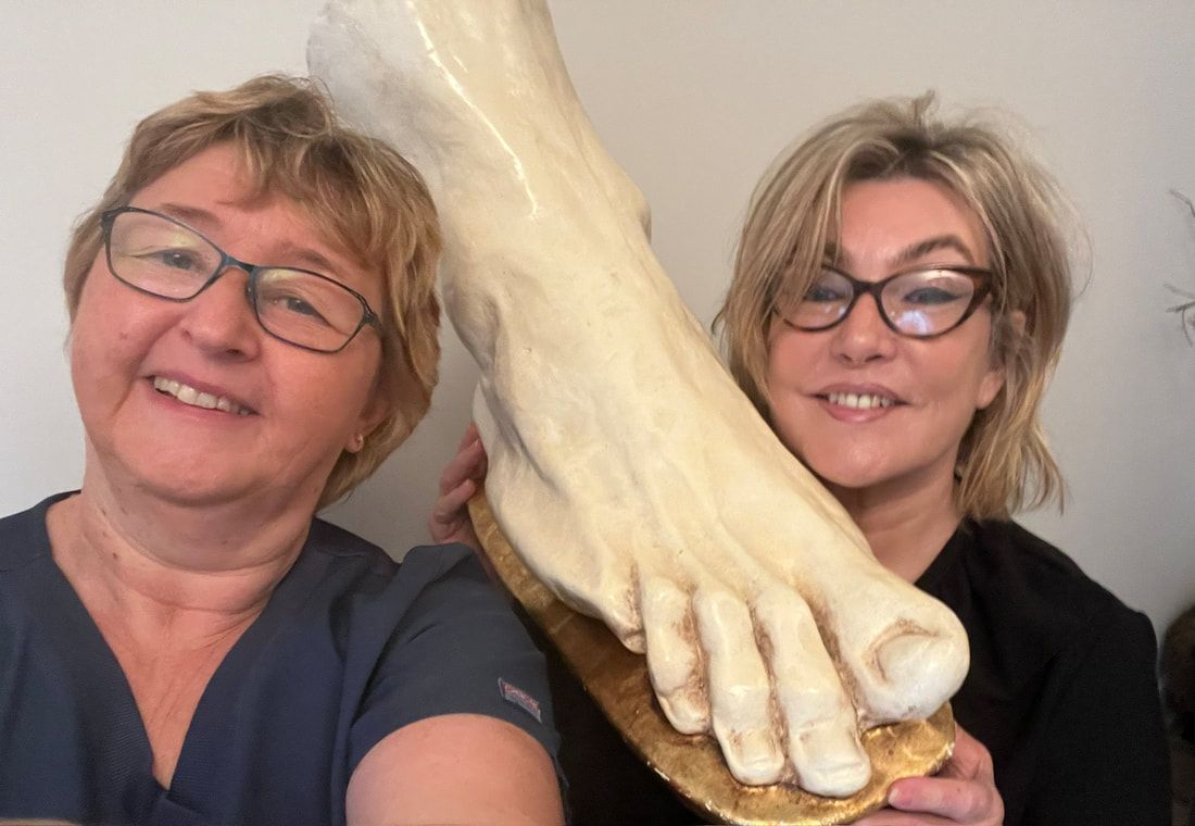 Toetal footcare Podiatrists, Cardiff & Pontypridd Two women standing next to each other holding a statue of a foot