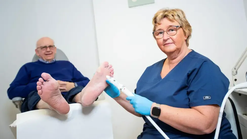Toetal footcare Podiatrists, Cardiff & Pontypridd A woman is cleaning a man 's feet in a chair.