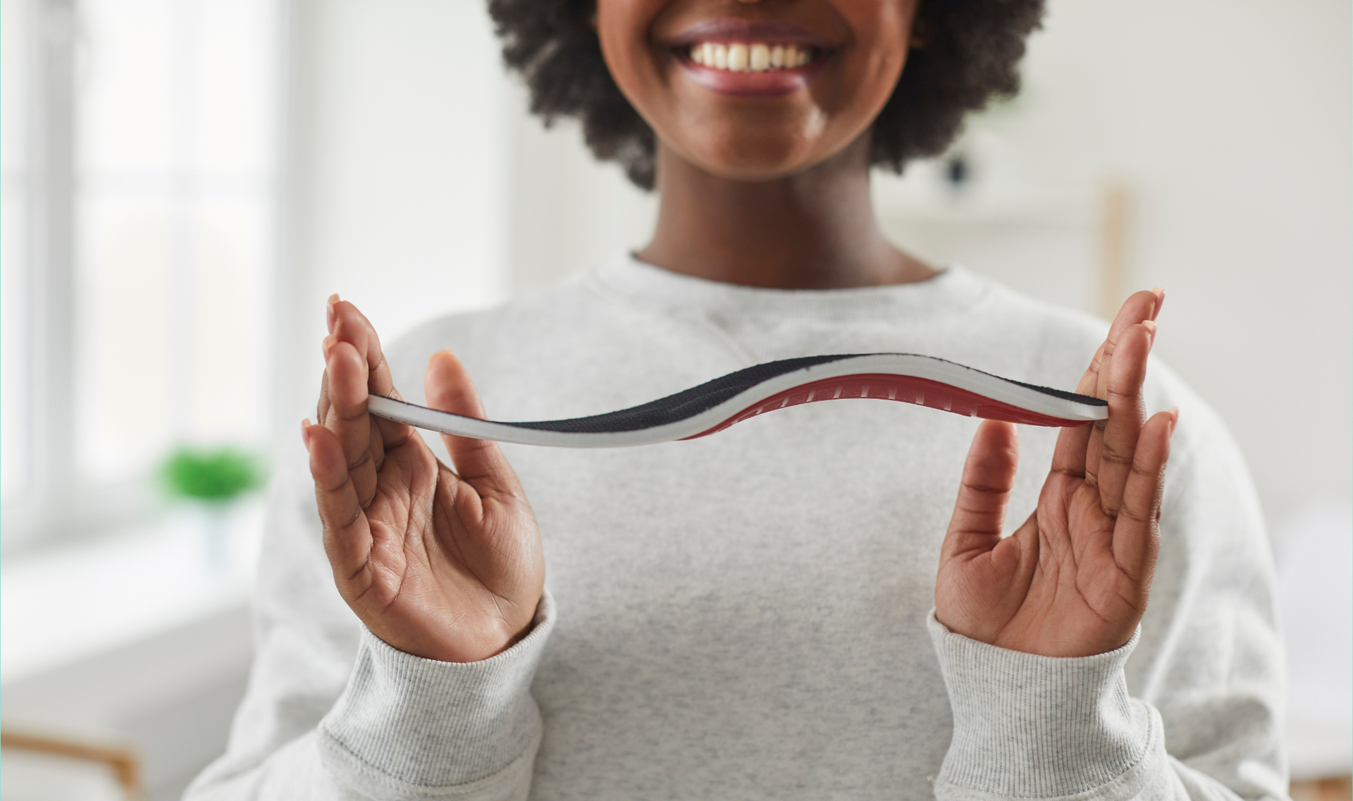 Toetal footcare Podiatrists, Cardiff & Pontypridd A woman is holding a pair of insoles in her hands.