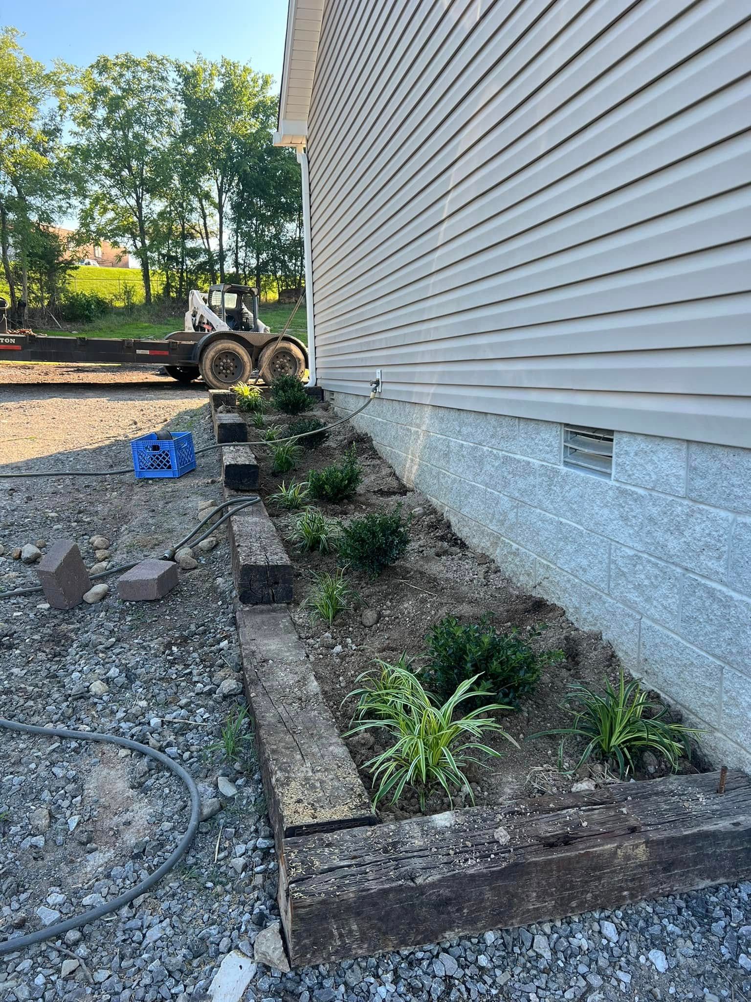 A house with a garden in front of it and a bulldozer in the background.